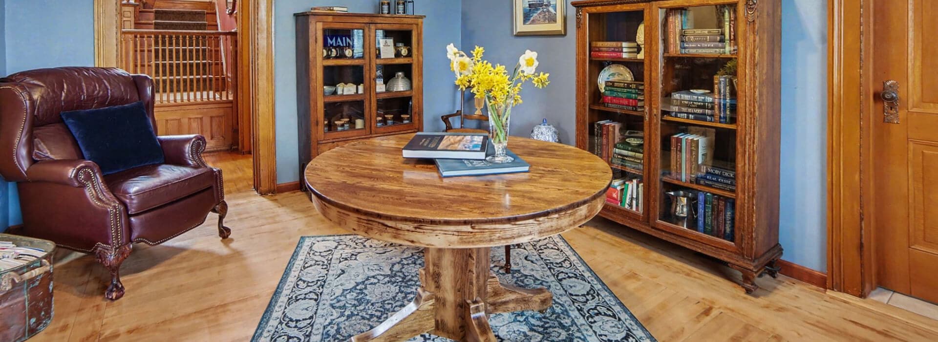 Cozy living room featuring a round wooden table, an armchair, and bookshelves filled with books and decor.
