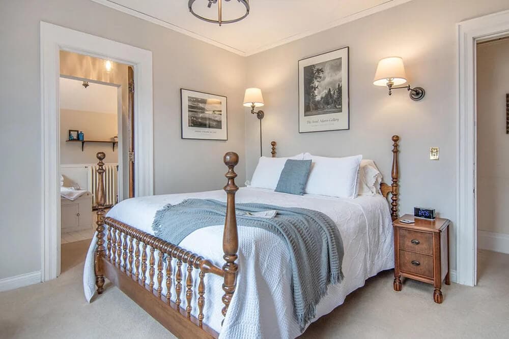 A cozy bedroom featuring a wooden bed, soft linens, and decorative wall art.